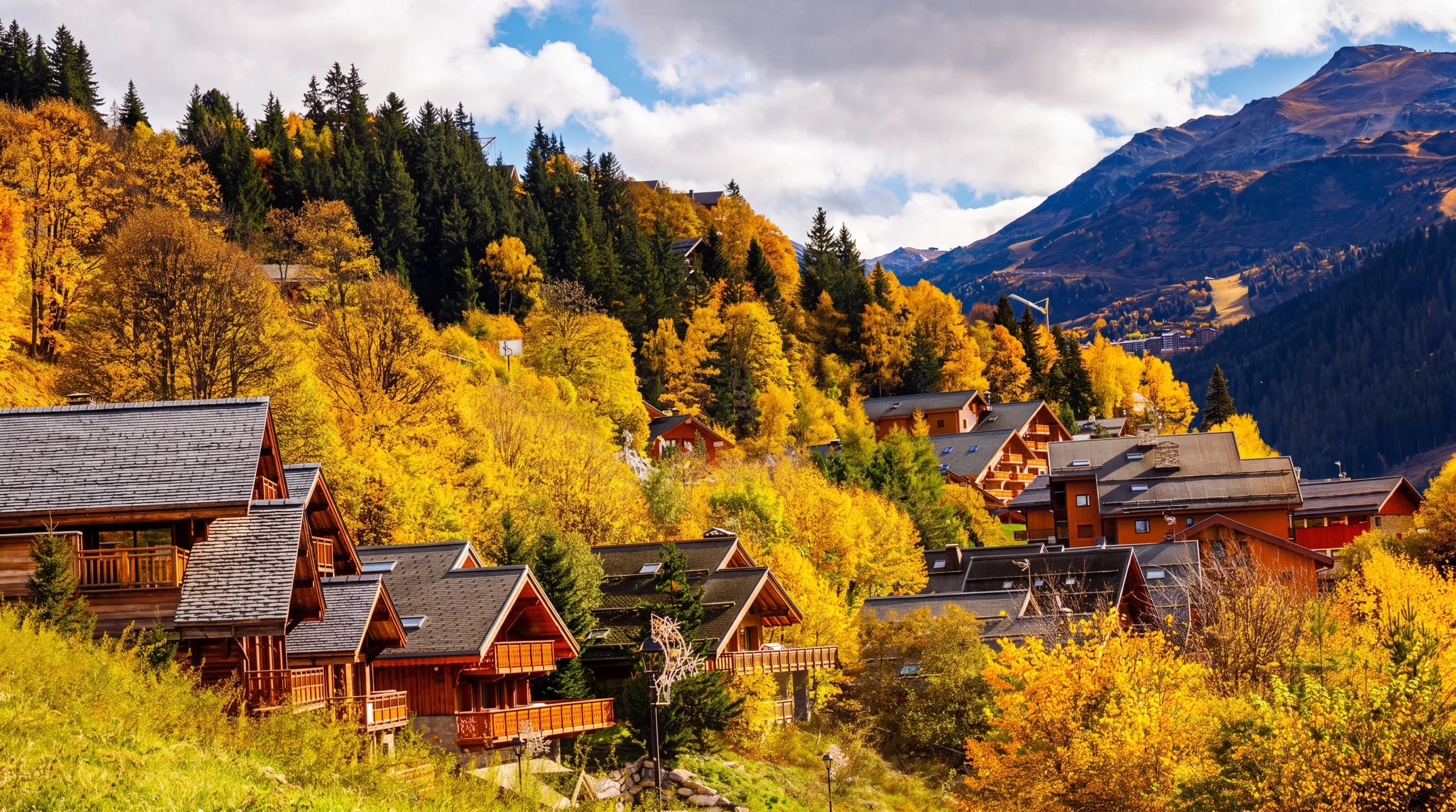 Hameau du Raffort à l'automne avec les versants colorés de la vallée de Méribel
